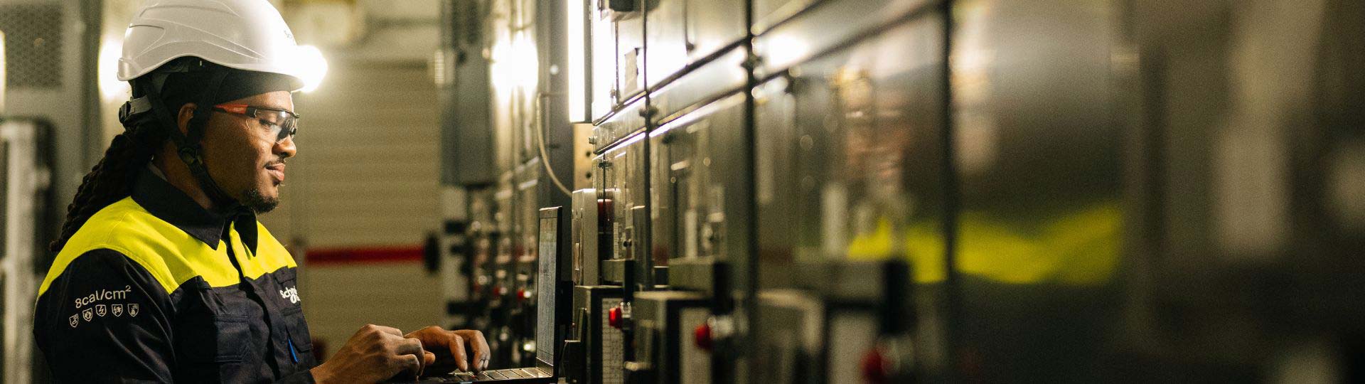 A person wearing a hard hat and working on a computer