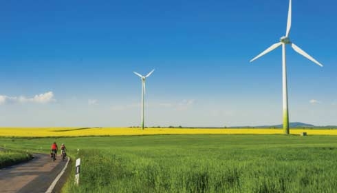 Ciclistas en un campo de molinos eólicos, energía renovable