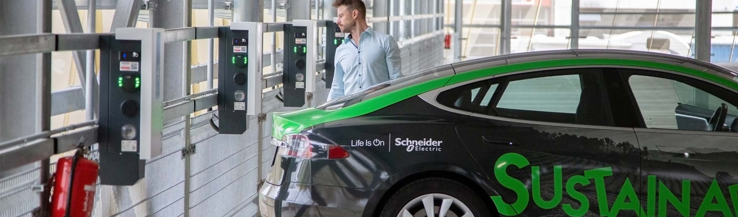 Sustainability Schneider Electric GmbH Tesla with EV Link chargers and SE employee
