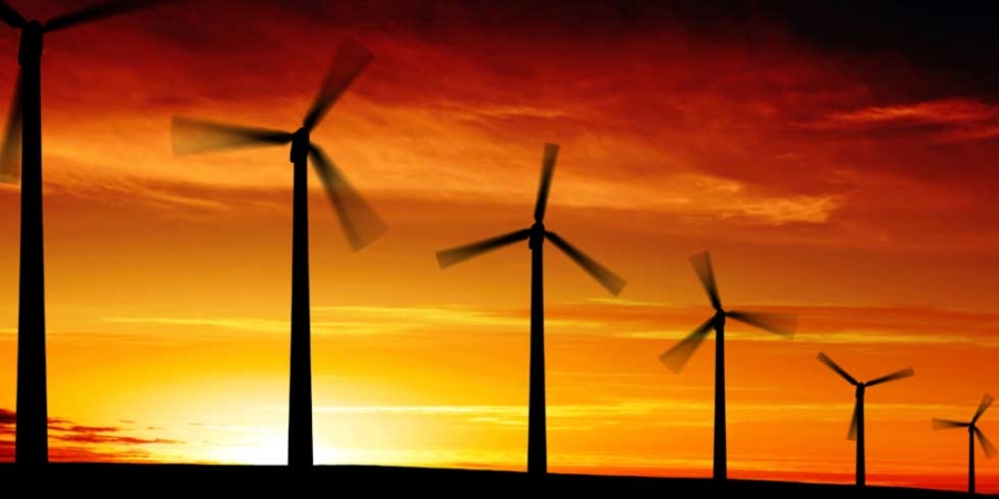 Windturbinen auf freier Fläche mit Sonnenuntergang im Hintergrund; Energie und Nachhaltigkeit.