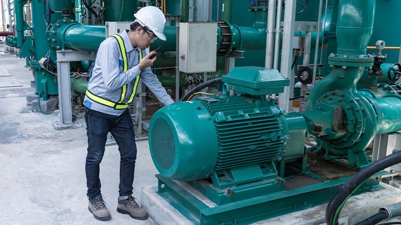 A person in a hard hat standing next to a large green machine