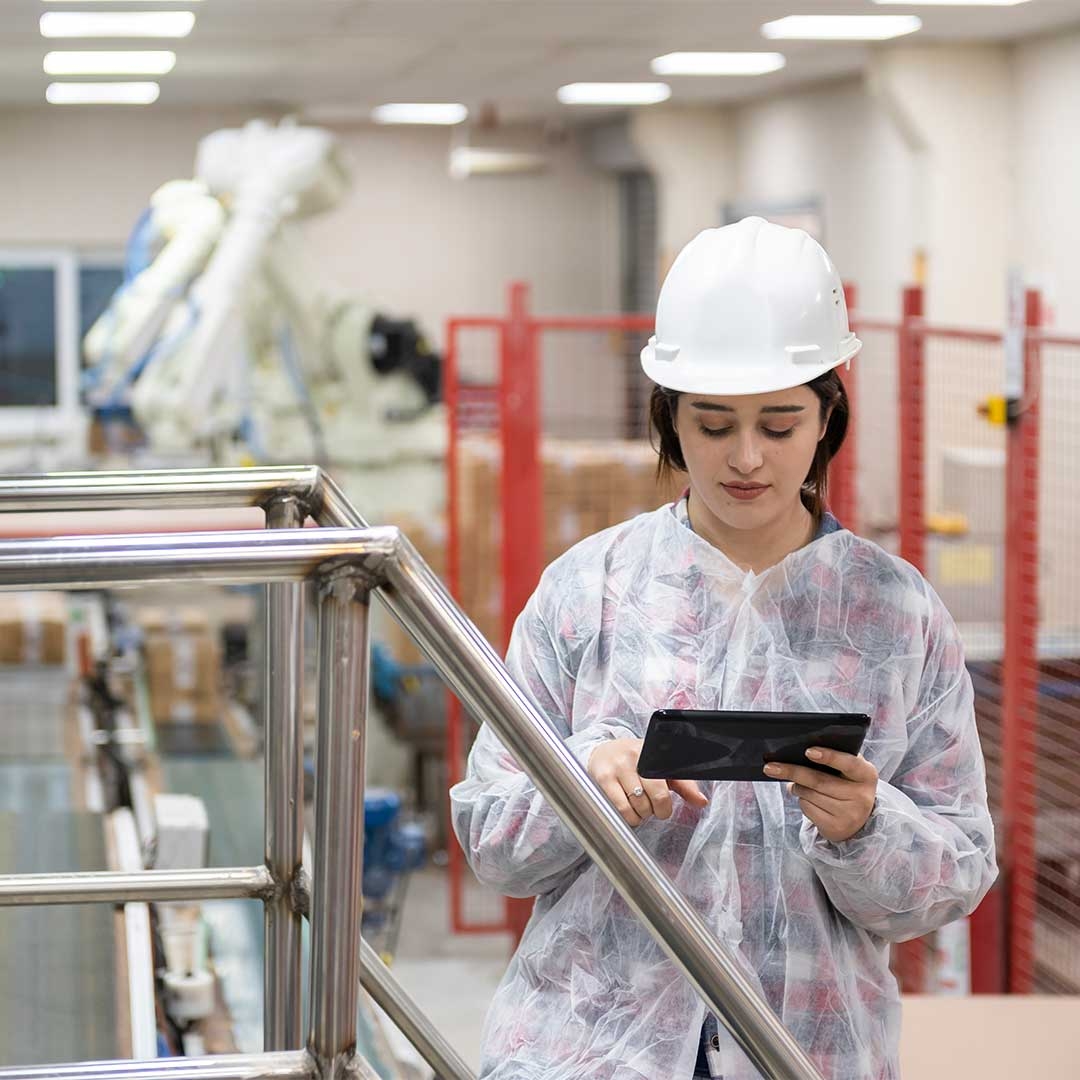 A person wearing a hard hat and a white helmet looking at a tablet