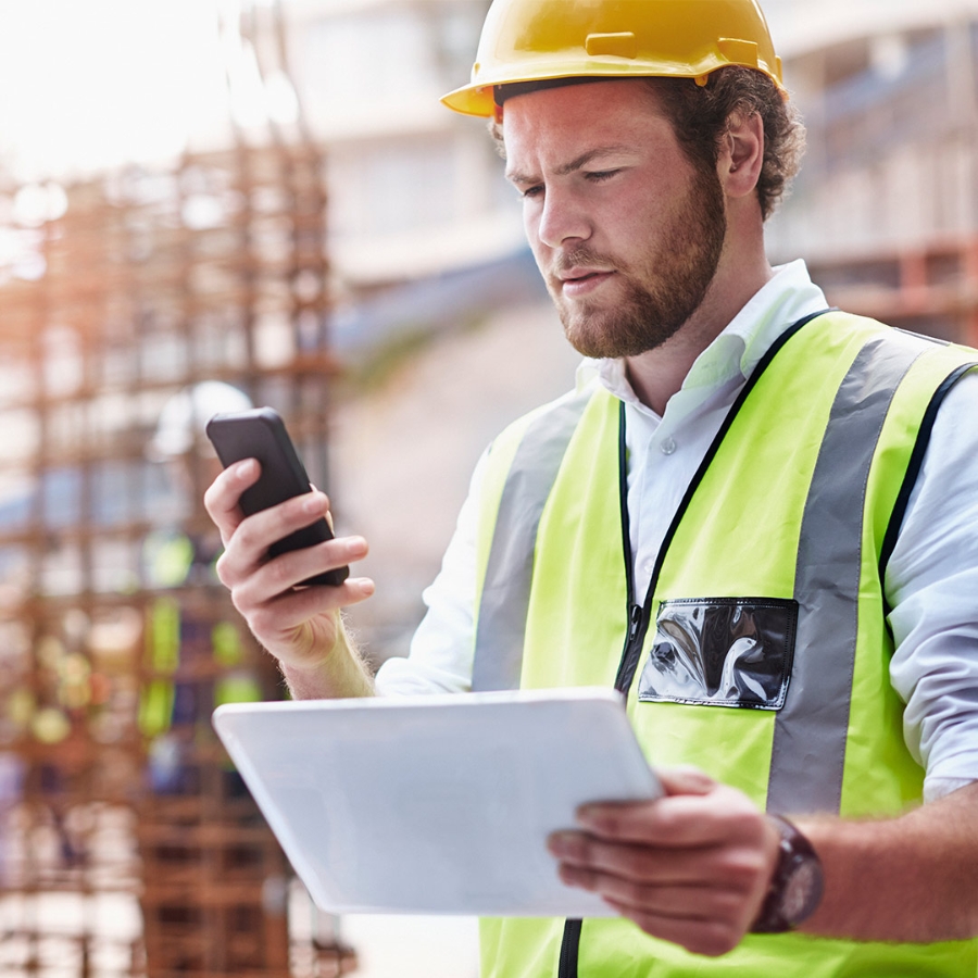 An Engineer on construction site with phone and tablet