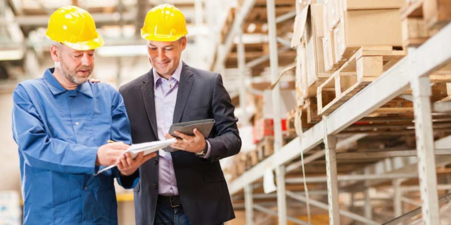Regardless of equipment age, we have service options that include Maintenance, Remote Management, Spare Parts, Training, Modernisation and Consultation; aligned to 5 key phases of the Asset Management Life Cycle. Worker and manager in warehouse.