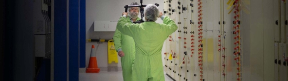 A person in green jumpsuits standing in a room with a mirror