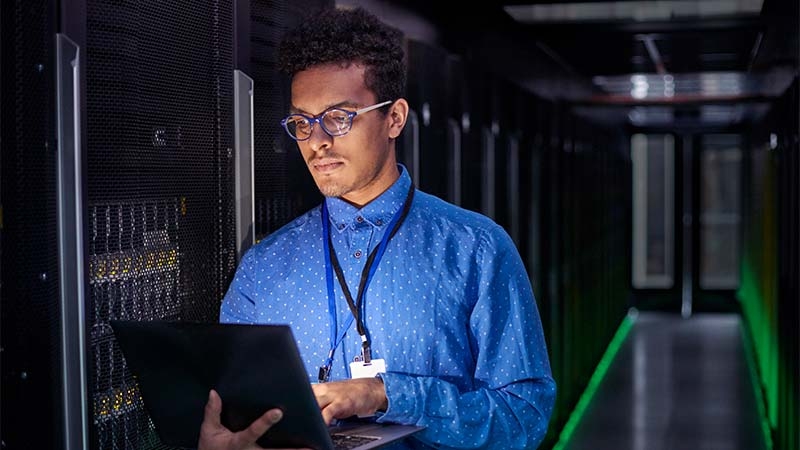 A person in a blue shirt holding a computer