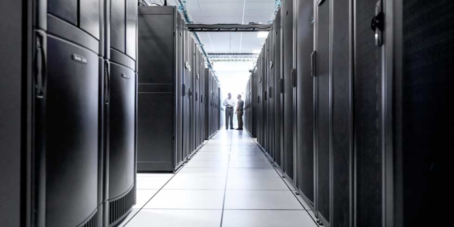 Two men standing in a row of data centres, data centre management, IT business.