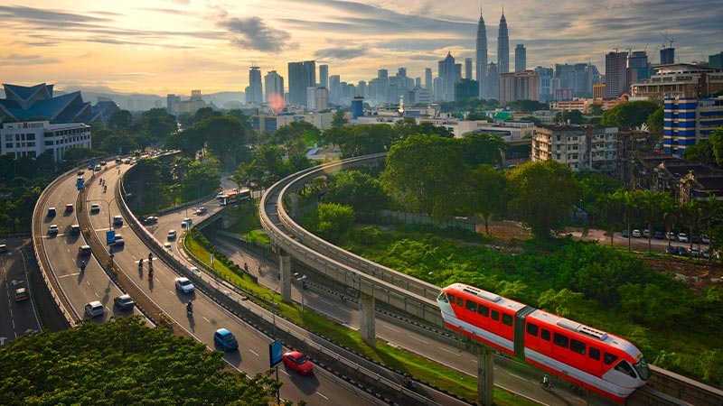 A red train powered by smart rail solutions on a monorail bridge over roads in a city