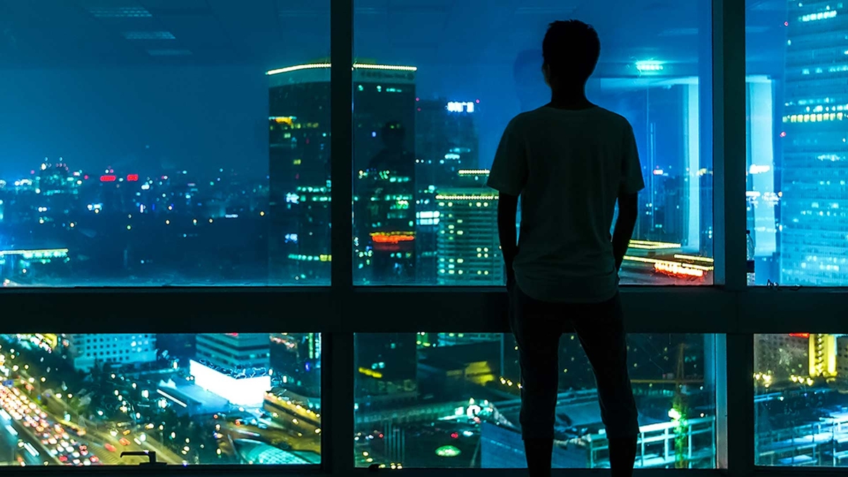 man is standing in front of the window and looking outside 