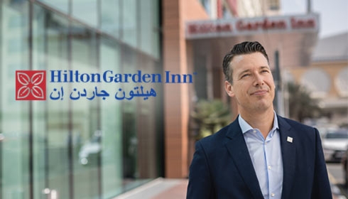 Zakenman staat bij hotelingang van Hilton Dubai Hilton Garden Inn