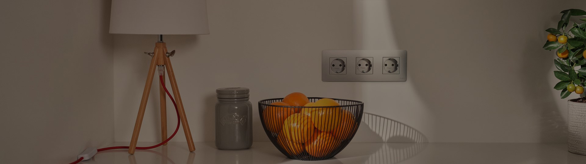 Basket of Oranges with table lamp and three sockets on wall