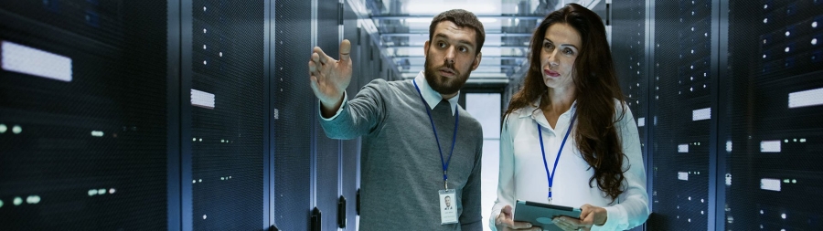 A male and a female employee discussing inside a server room of a data center