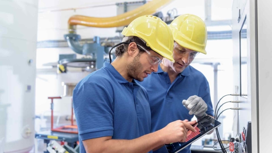 Two employees wearing protective hats and discussing at a smart factory