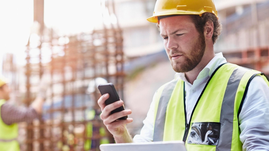 man using phone while holding a digital tablet in the construction industry
