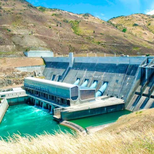 Barragem de hidroelétrica com pasto e colinas, gestão hídrica, eficiência energética.