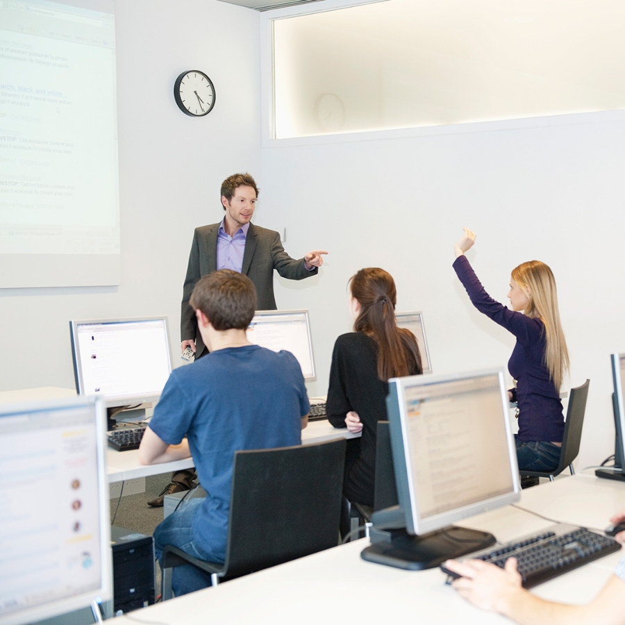 Students sitting in a classroom and a male teacher is teaching to them