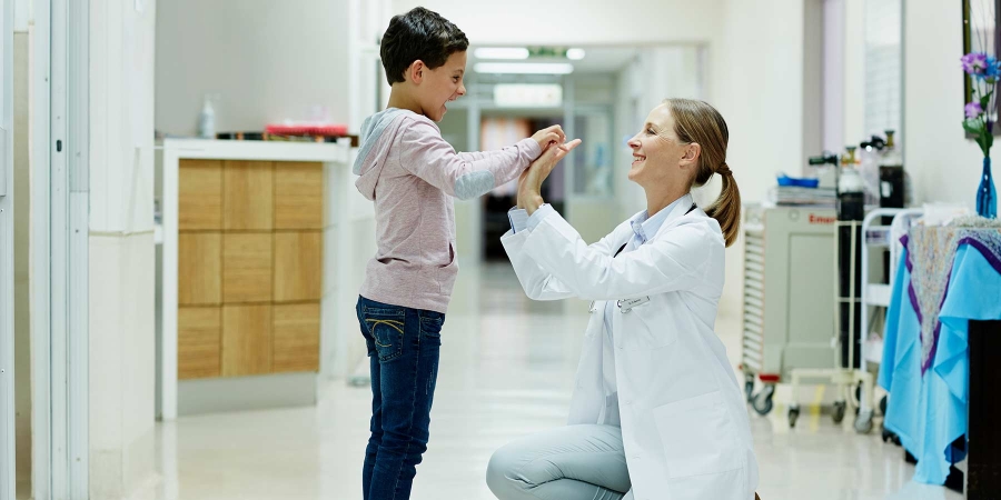 A female doctor interacting with a kid in the corridor of hospital