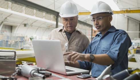 Workers at laptop in manufacturing plant