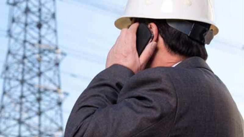 A person wearing a hardhat talking on a cell phone