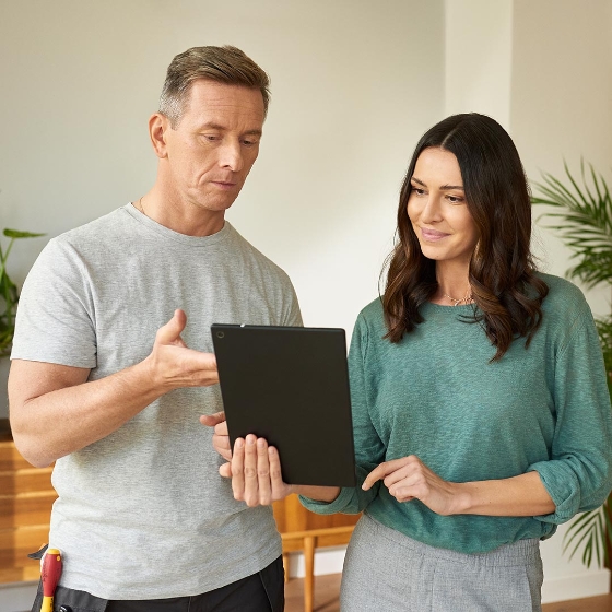 man and woman talking while holding a digital tablet in the smart home