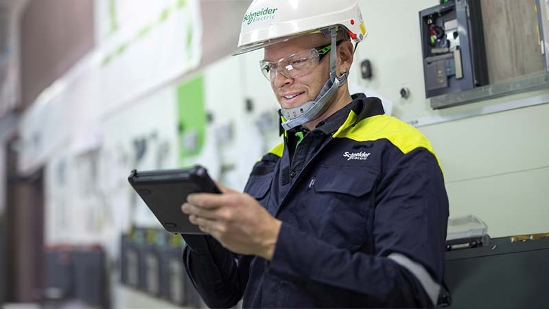 A person wearing a hard hat and a helmet using a tablet