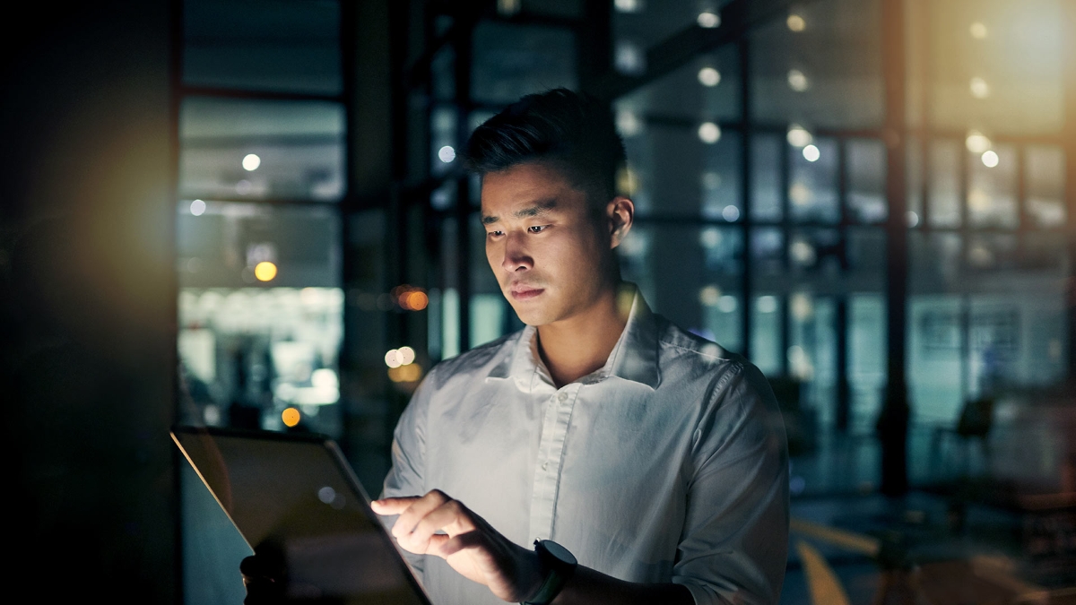 Young businessman using a digital tablet during a late night in a modern office