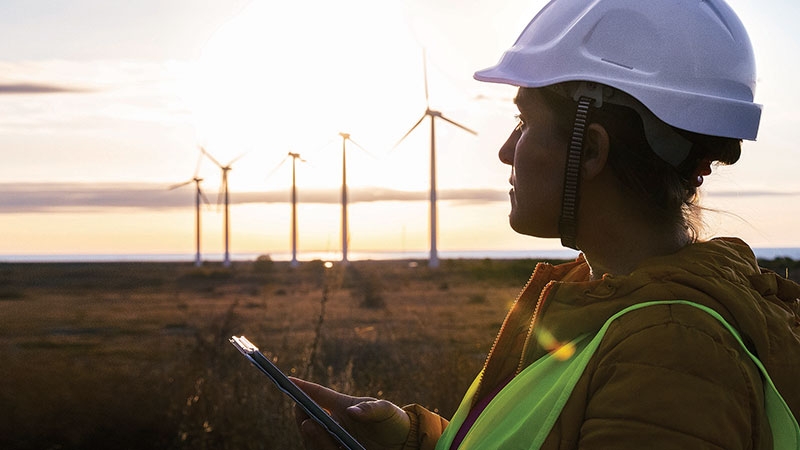 Frau mit Helm vor Windrädern
