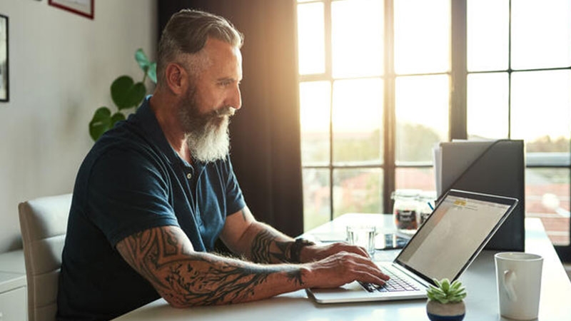Man with tattoos working on laptop