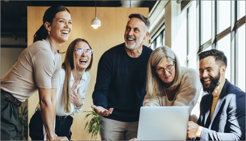 A group of people laughing and looking at a computer