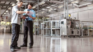 Sustainability consulting between two factory workers in bottling plant, food and beverage.