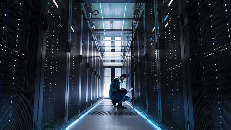 A person kneeling in a server room