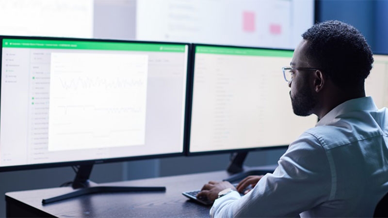 A person sitting at a desk with two monitors