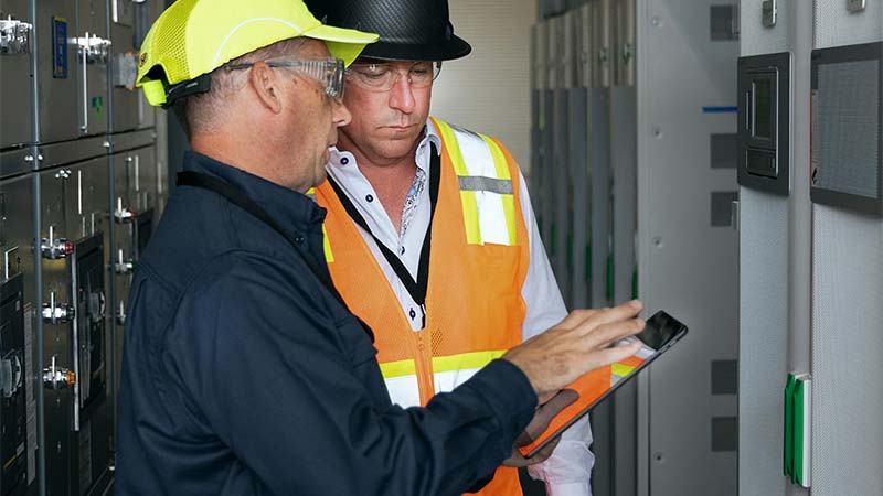 A few men in safety gear looking at a tablet