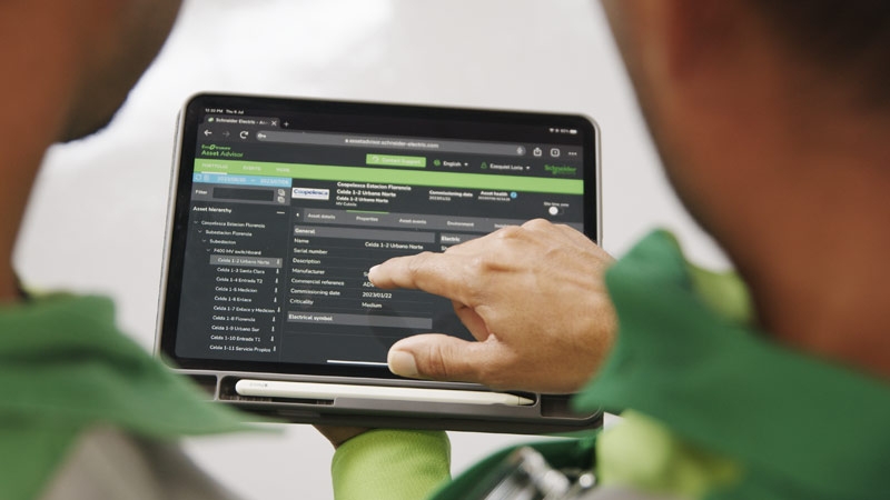 Two Coopelesca employees holding a tablet while viewing EcoStruxure Asset Advisor software.