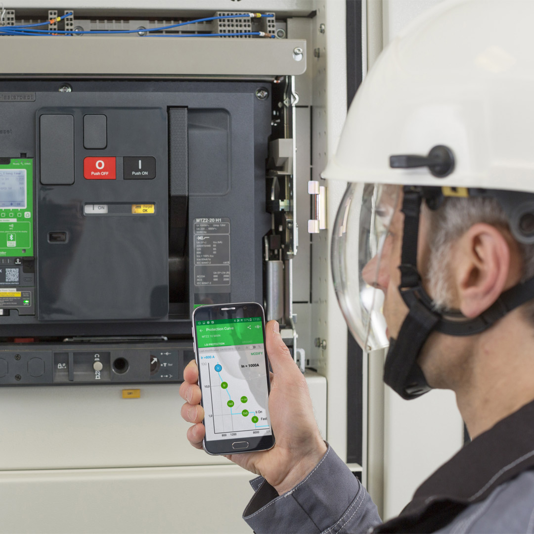 Engineer holding mobile and working with electrical machine
