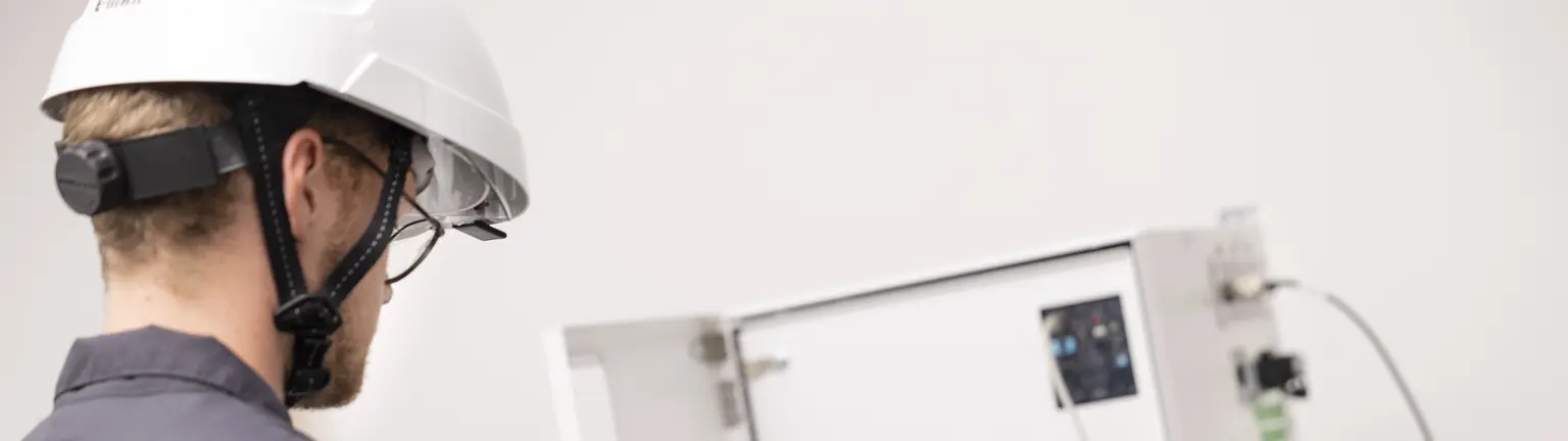 Technician in Schneider Electric uniform inspects electrical equipment with a tablet