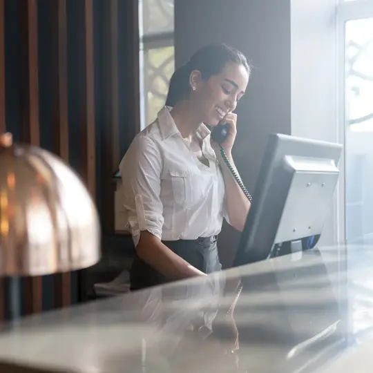A hospitality professional standing behind a desk talking on the phone