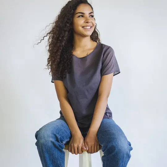 A person wearing a pair of  jeans sitting on a stool