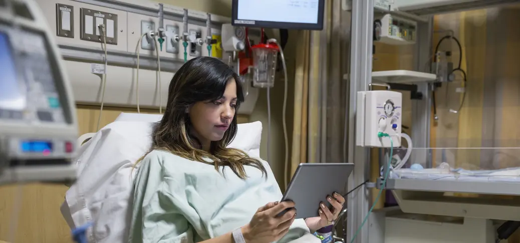 Vrouwelijke patiënt die een tablet gebruikt in een ziekenhuisbed