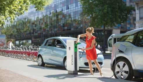 Woman using an electric charging station to power her vehicle. Sustainability, EVlink