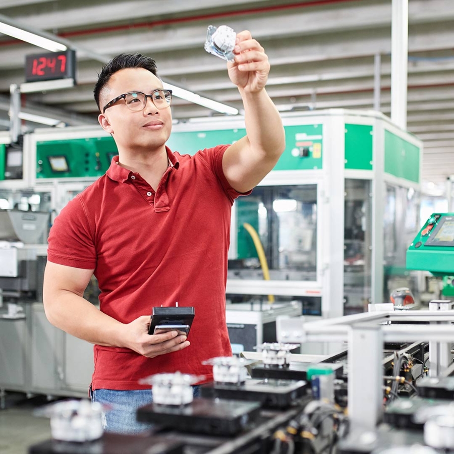 A young male employee inside a factory holding a Merten product in hand