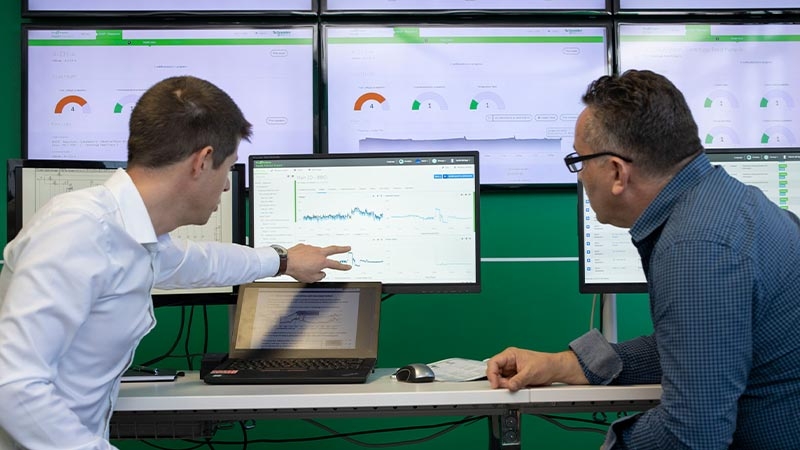 Two digital services consultants are remotely monitoring the power distribution of on-site equipment 