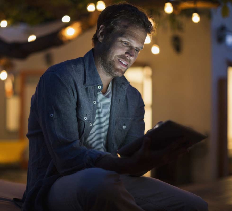 Man using digital tablet on dark patio