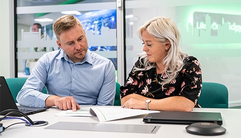 A person and person sitting at a table looking at a paper