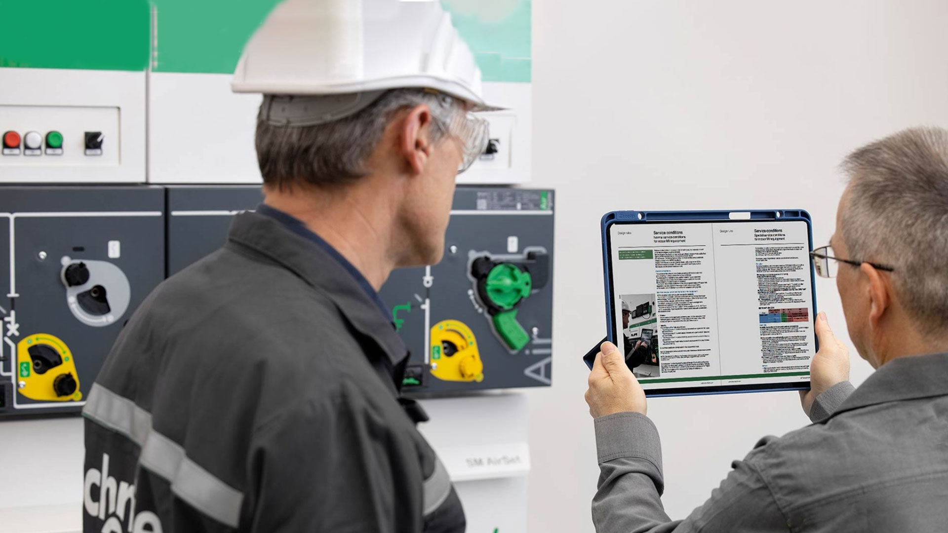 two technicians reviewing medium voltage installation maintenance report on digital tablet