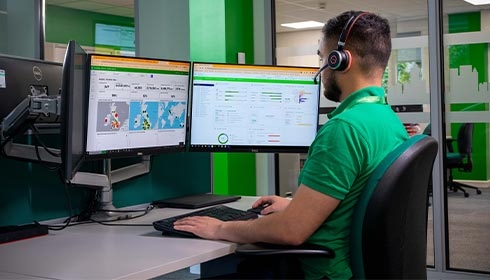 A person wearing a headset and sitting at a desk with two computer screens