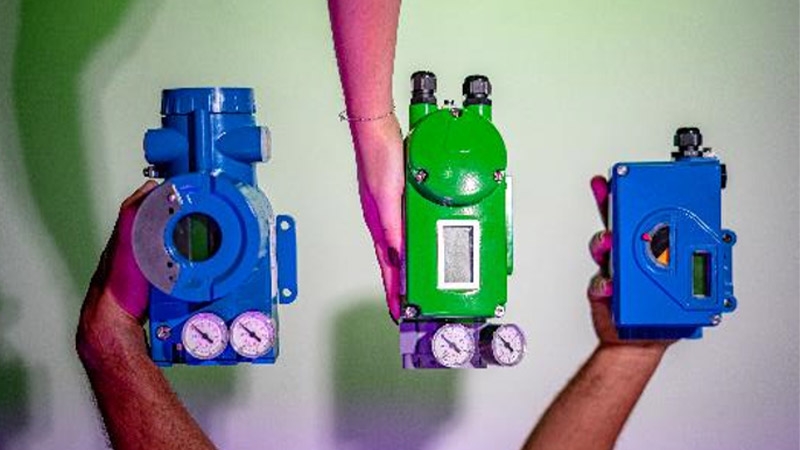 A group of hands holding blue and green devices