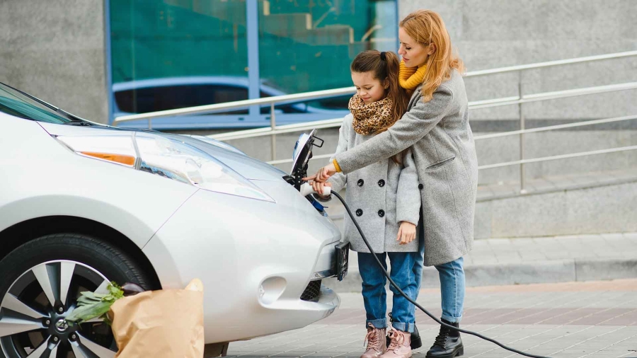 mom and daughter charging their electric car