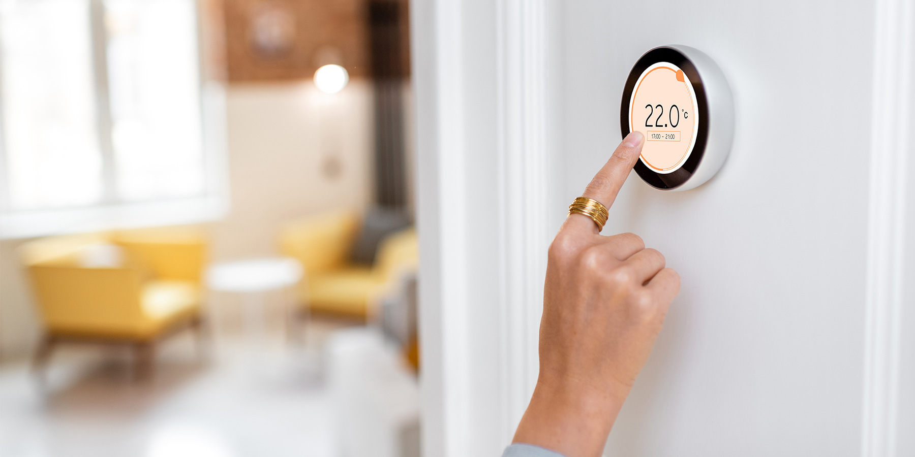 hand pointing a modern thermostat in smart home