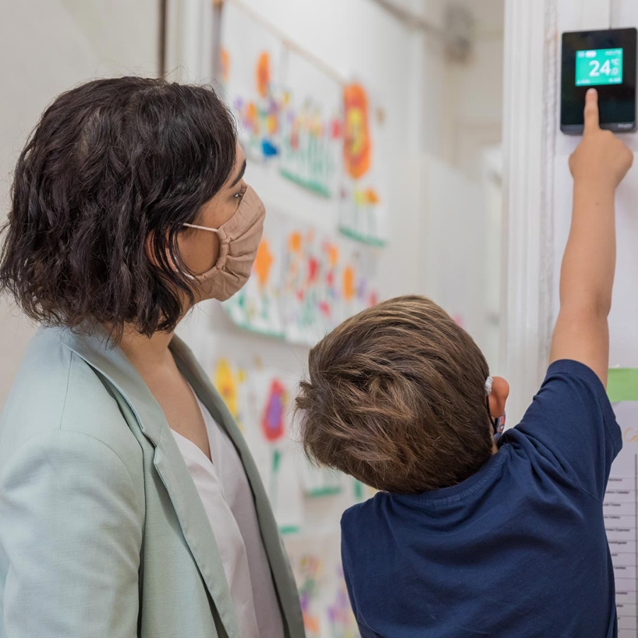 A child pointing towards a digital meter and a woman is behind him